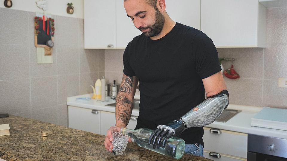 Maurizio si versa un bicchiere d'acqua con la sua mano bebionic e MyoPlus
